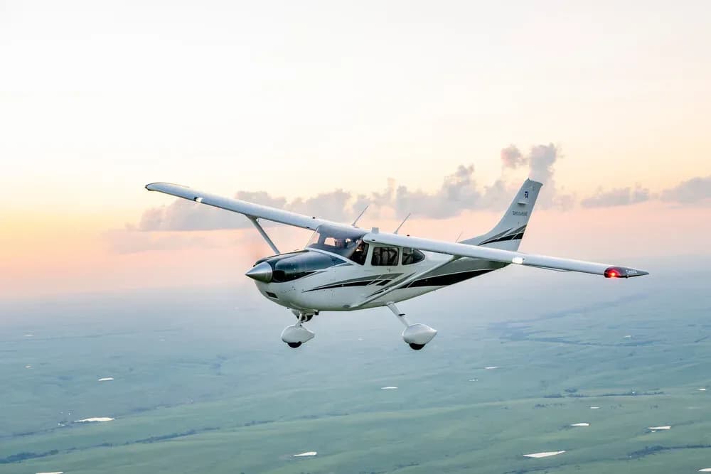 Einmotoriges Kolbenmotorflugzeug im Flug über bewaldetem Gelände