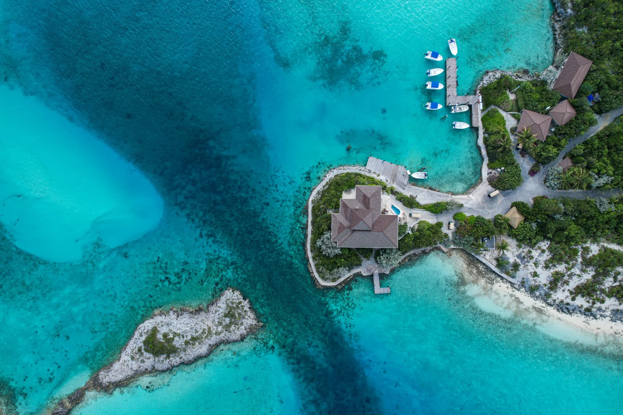Fowl Cay von oben: die Villa auf der Landzunge, die Stege mit den Motorbooten und die helle Sandbank im türkisen Wasser